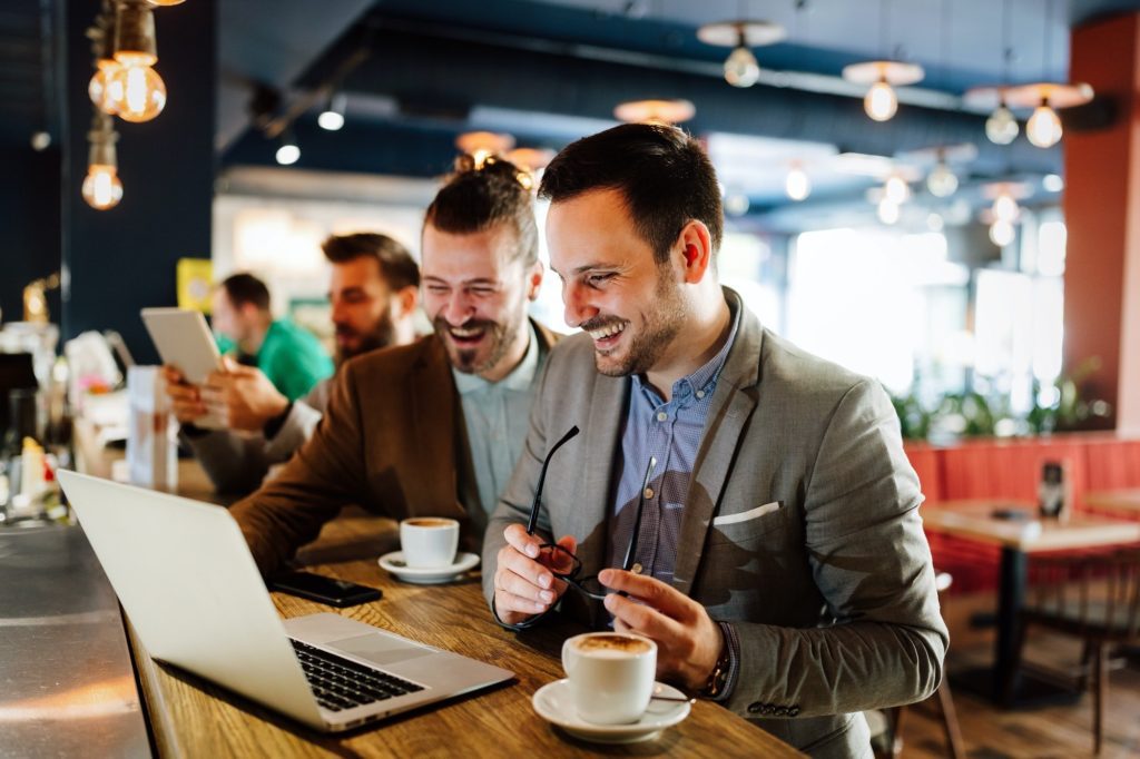 Happy business people talking and laughing together at cafe