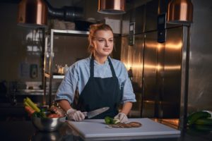 European beautiful female chef in a dark restaurant kitchen